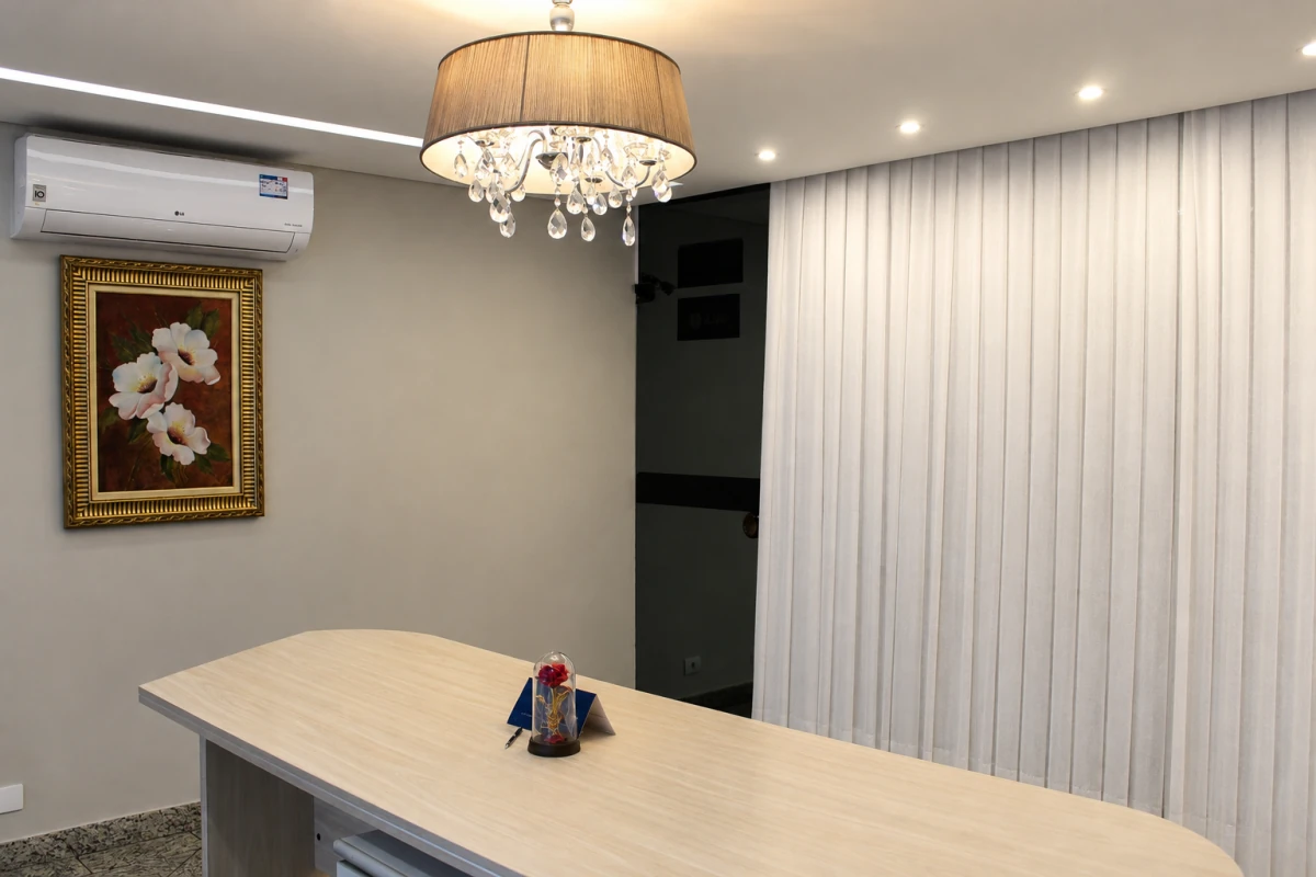 Sala de casamento com mesa de celebração, lustre e cortinas claras